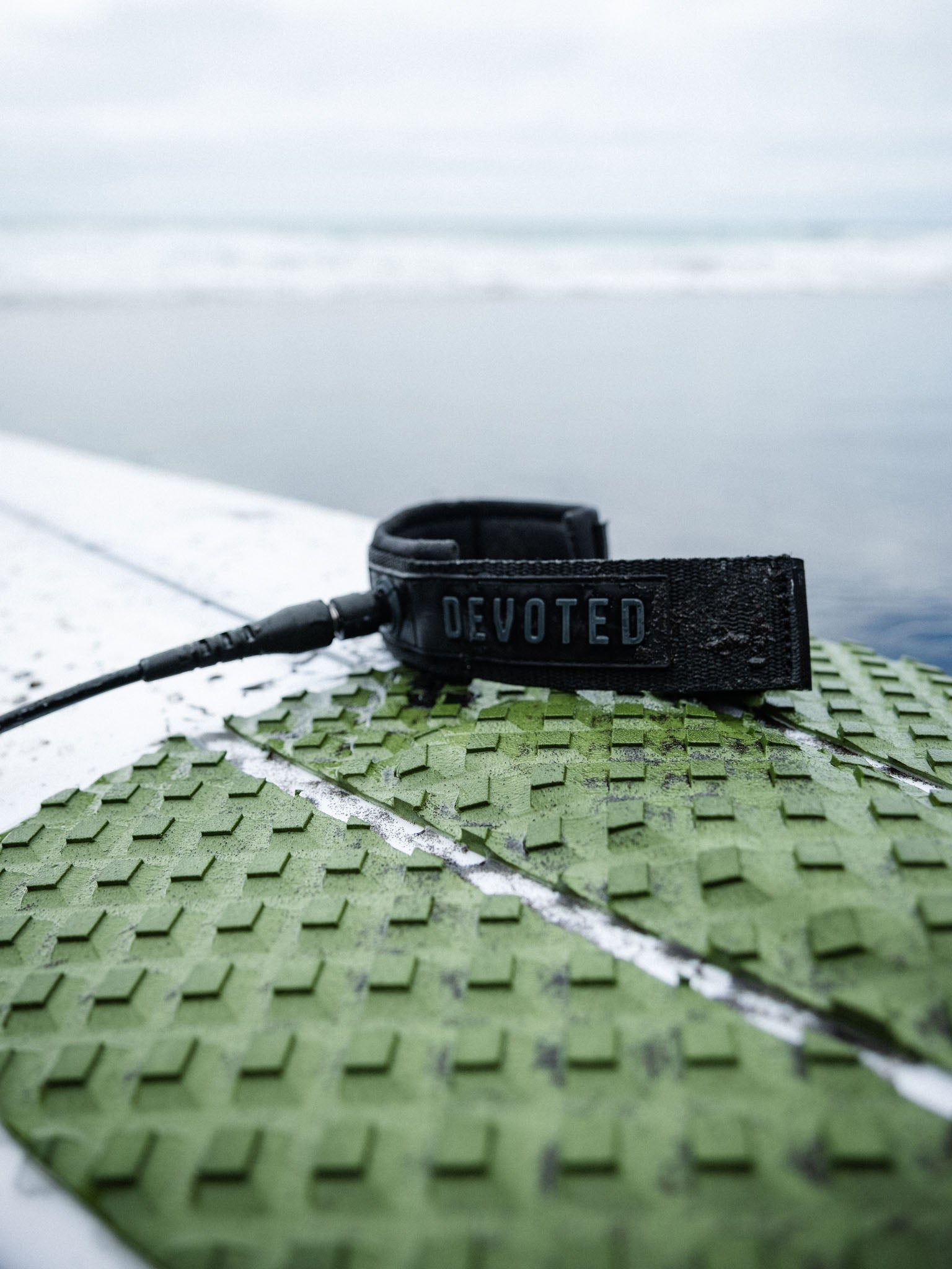 “Surfer attaching Core Series 6mm leash outside at surf spot”

