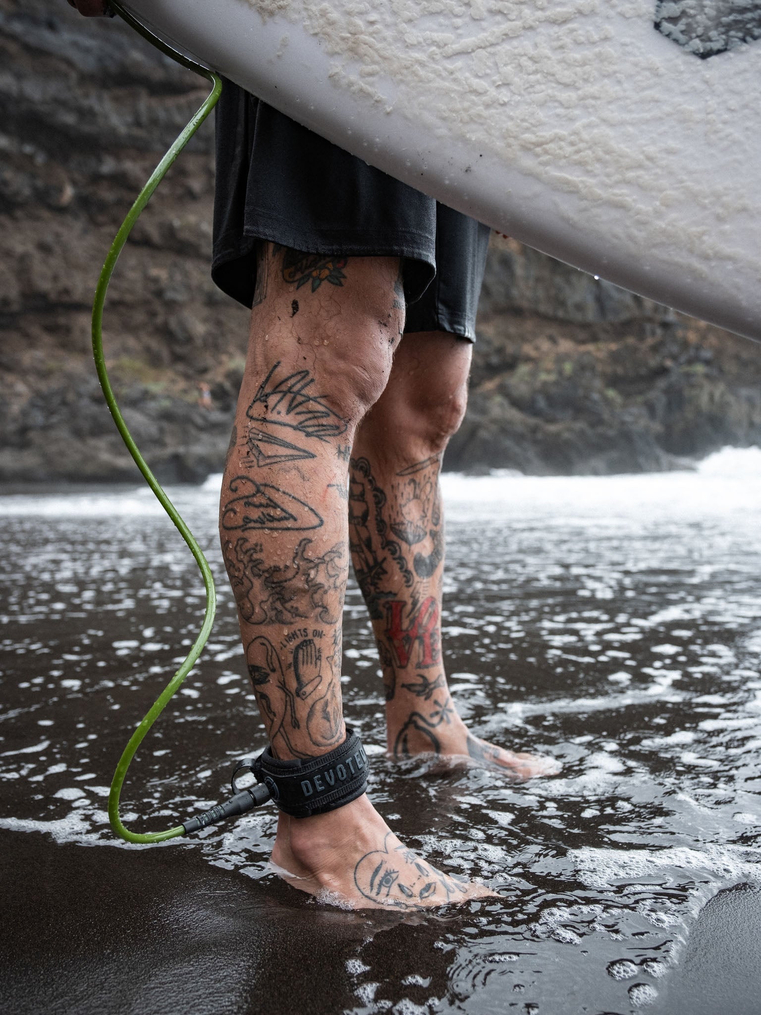 “Leash trailing from surfboard on wet sand”
