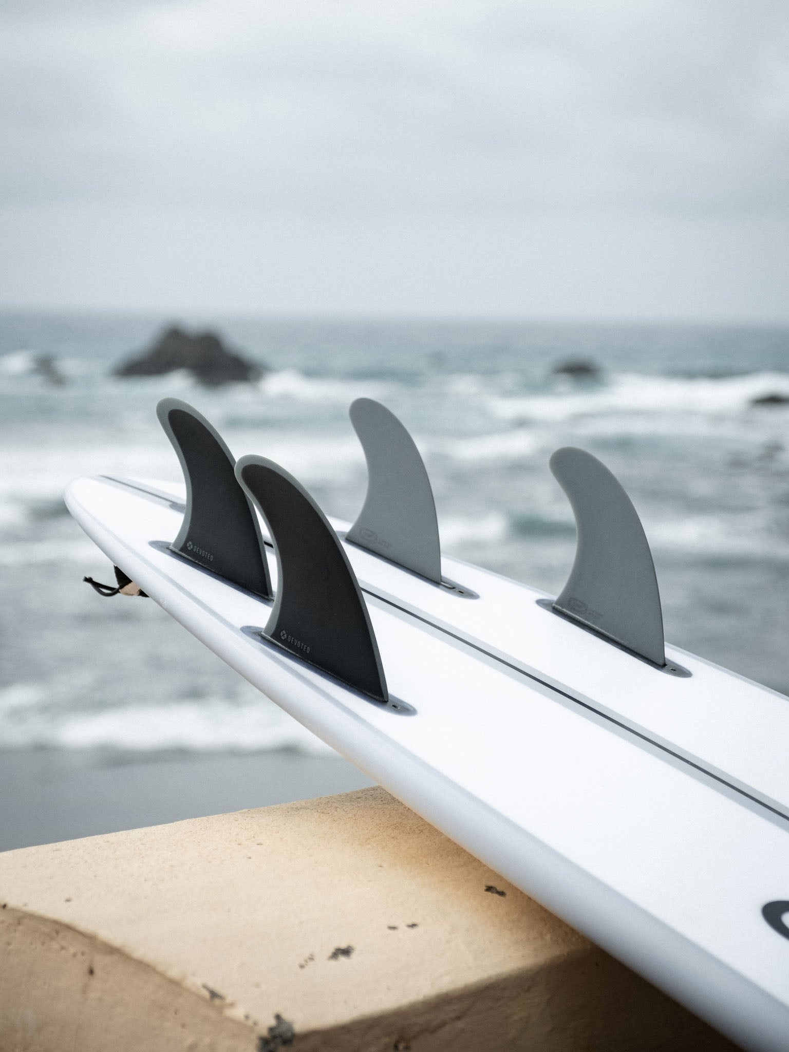 “Close-up side view of CSF Quad single-tab fins on board, showing placement and fibreglass material detail”