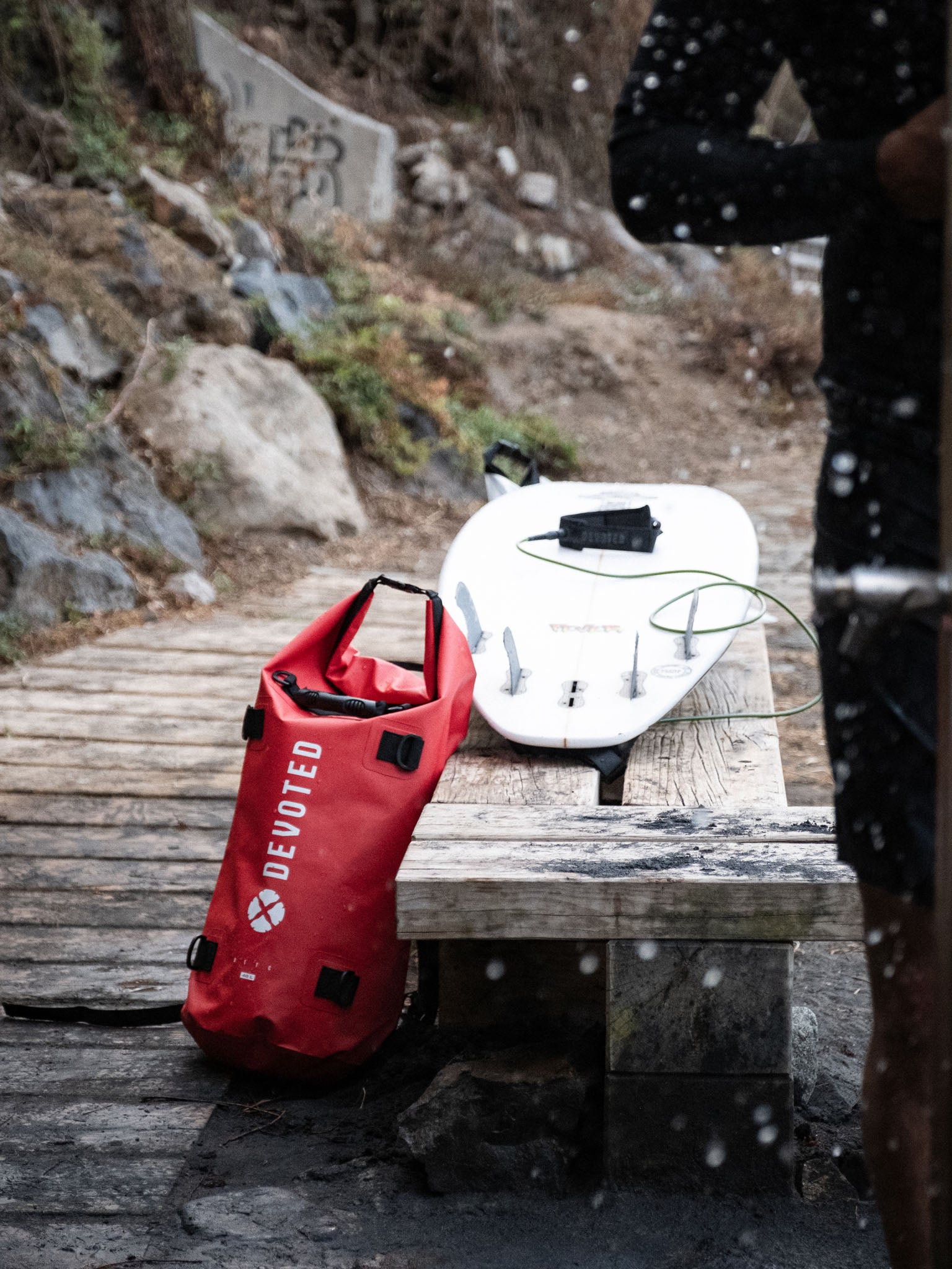 “Red Devoted dry bag backpack worn outdoors near beach or trail”
