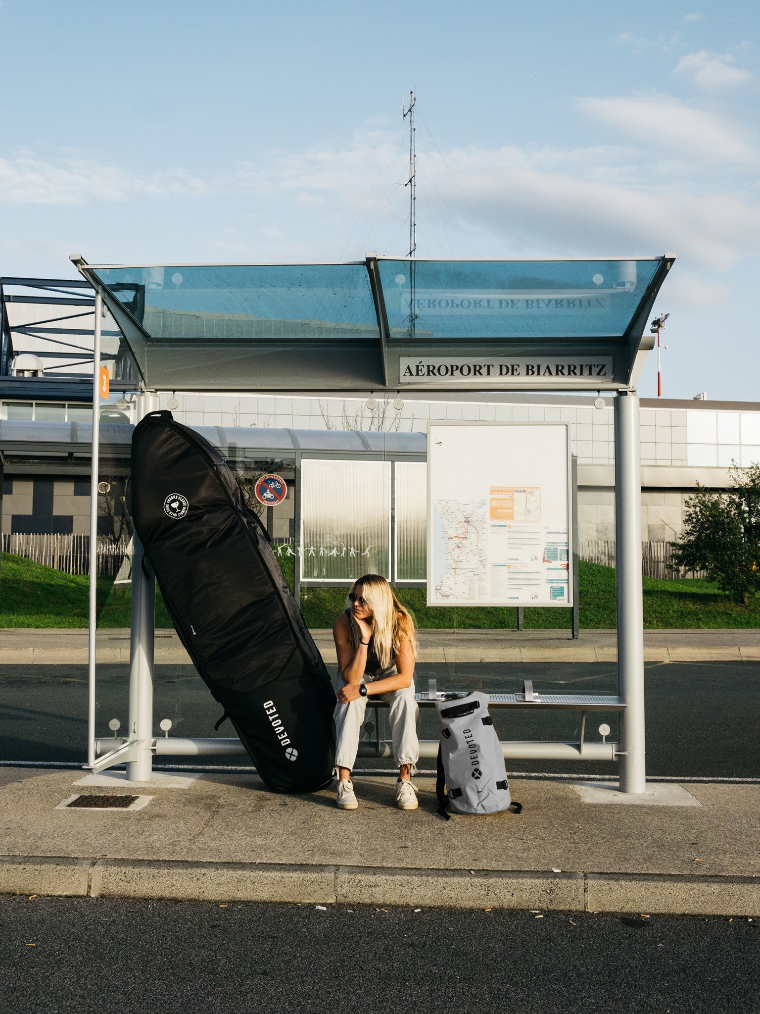 “Surfboarder carrying Devoted Fish 10mm boardbag outdoors, showing portability and size”
